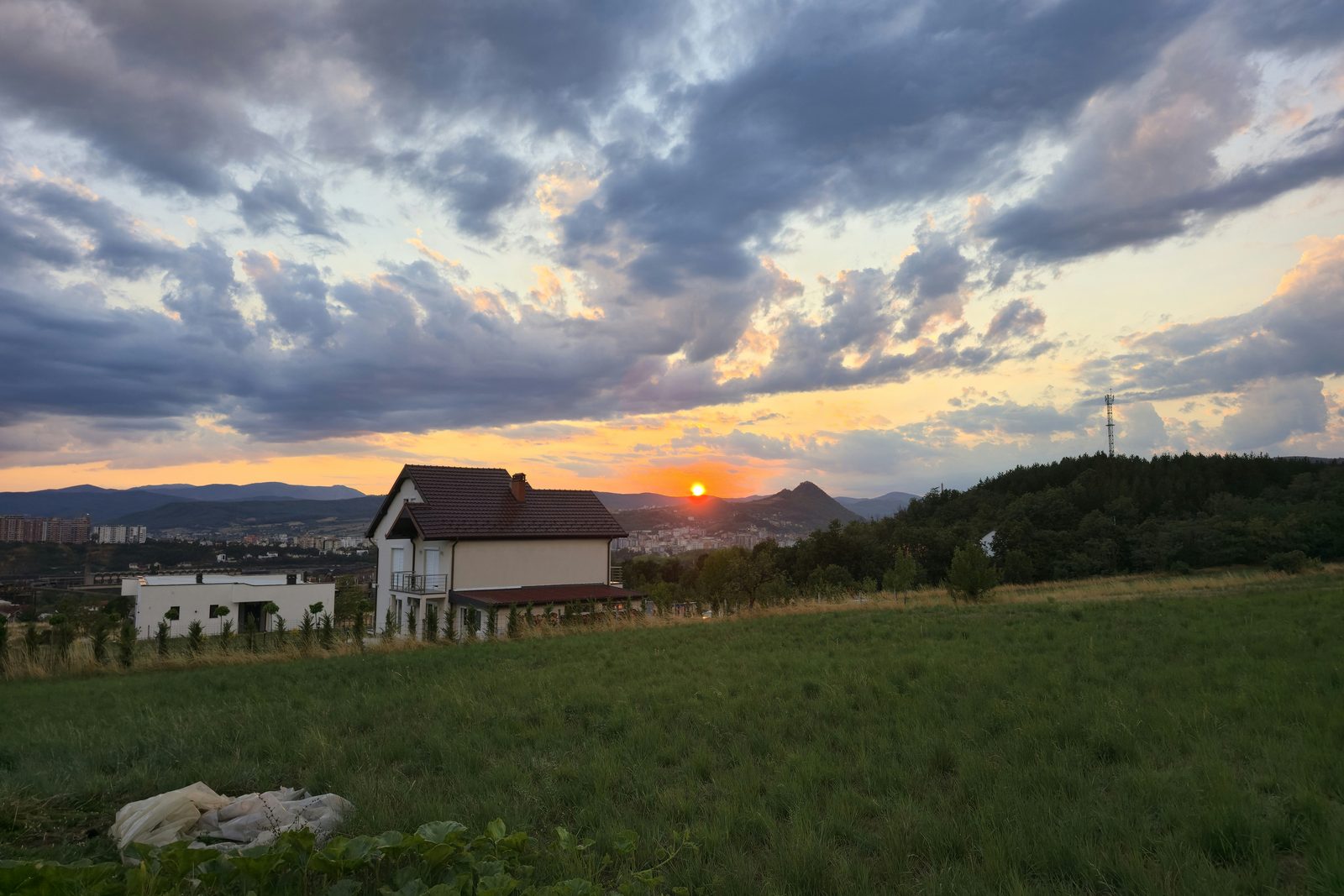 A house in open fields at golden hour with hills behind