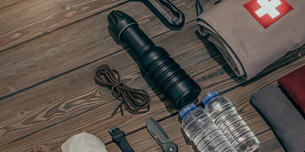 Emergency kit with water, first aid, flashlight, tools, and blanket.