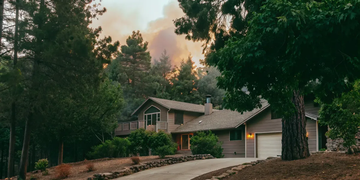 Wildfire smoke approaches a house. Wildfire preparedness plan is crucial.