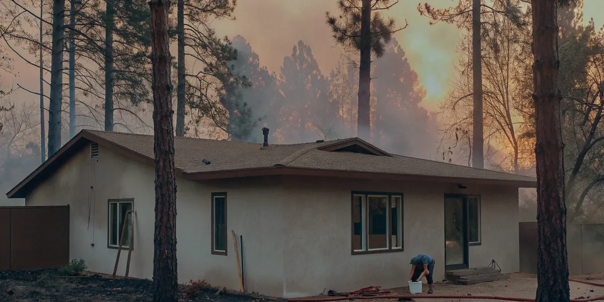Homeowner preparing a house for a wildfire using a proofing checklist as smoke appears in the background.