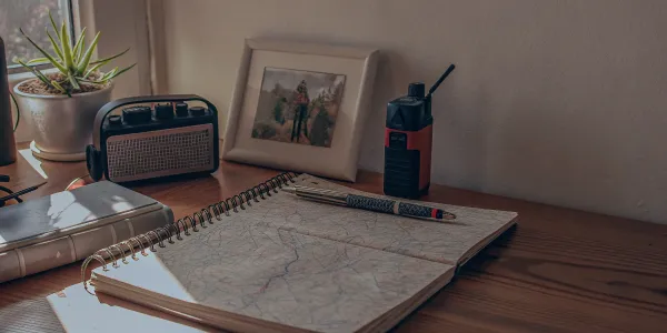 A family's wildfire emergency communication plan laid out on a desk with a map and two-way radio.